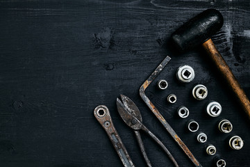 Copy space of working tools on a black wooden surface. Nippers, wrench keys, pliers, screwdriver, hammer. Top view.