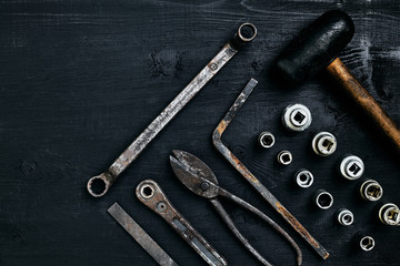 Copy space of working tools on a black wooden surface. Nippers, wrench keys, pliers, screwdriver, hammer. Top view.