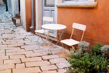 Fototapeta na wymiar Chairs and a table in garden. Steel chairs and a table standing in a beautiful garden at sunny day. Patio furniture. A set of chairs and a small table set outdoor.