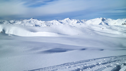Fresh snow on ski pistes, covering valleys and peaks, with rugged mountain tops panorama, on a clear winter day, Les Trois Vallees, Alps, France .