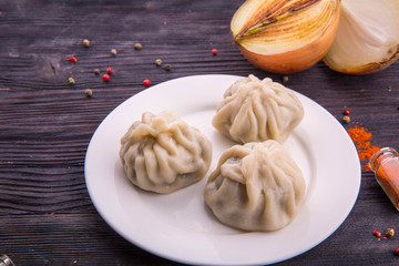 Meat dumplings on a white plate with pepper and onions