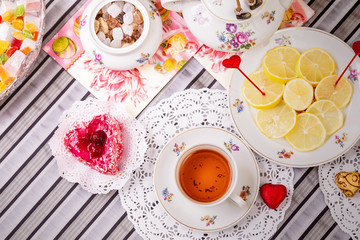 Porcelain cup of tea with lemon and sweets