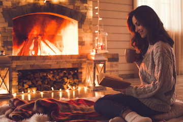 Young woman near fireplace at home winter concept