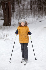 Young girl amateur sportsman skiing in winter snowy forest, full-length