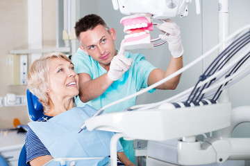 Obraz premium Dentist explaining to patient correct tooth brushing
