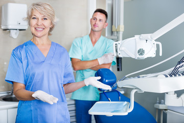 Dentist near dental chair, welcoming patient to office