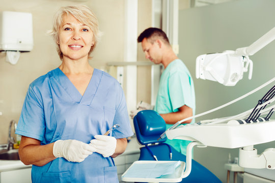 Dentist near dental chair, welcoming patient to office