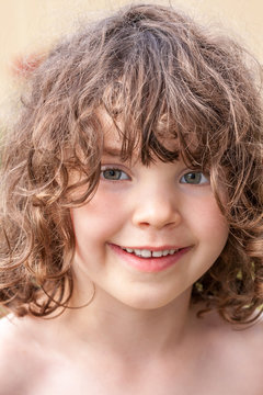 Close up summer portrait of a cute pretty smiling preschool girl with tangled hair.