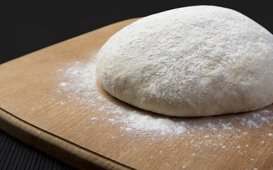 Fototapeta na wymiar Loaf dough on wooden board on black background