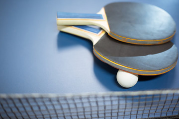 Two ping-pong rackets and white balls on the professional table with net
