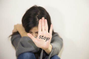 Girl being struck. Portrait of young girl with bruises on her face showing stop sign, palm in focus
