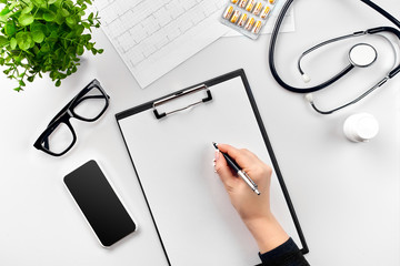 Doctor's work with stethoscope and copybook on hospital desk background. Top view