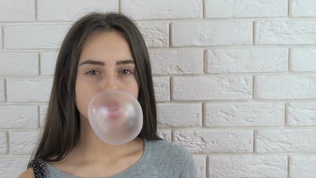 Funny girl with chewing gum. Pretty teenage girl blowing bubble gum.