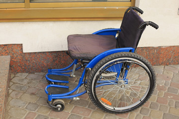 Empty wheelchair next to a shop on the street.
