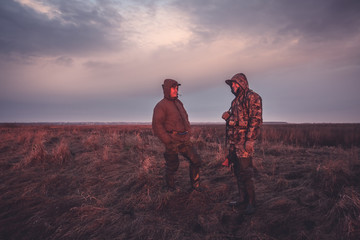 Hunters during hunting spring season in rural field at sunrise