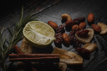 Mix of nuts, dried fruits and herbs on a black rustic background.