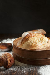 freshly baked bread on a wooden table on a dark background