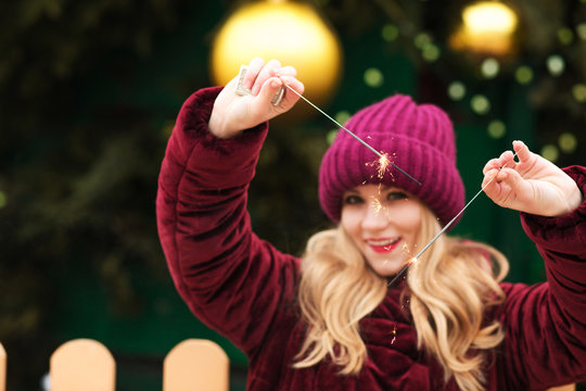 Adorable blonde model holding glowing Bengal lights at the main Christmas tree in Kiev. Blur effect
