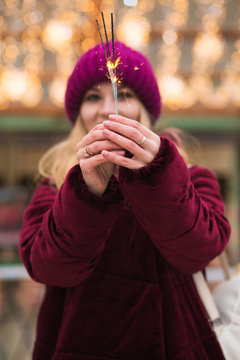Magnificent blonde girl holding glowing Bengal lights at the Christmas fair in Kiev. Blur effect