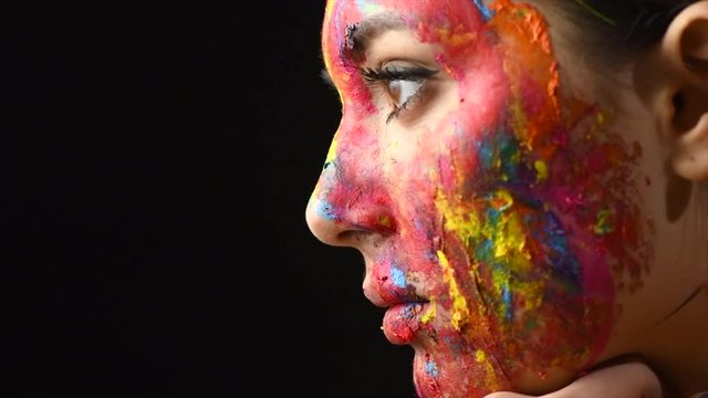 Beauty model girl with colorful paint on her face. Multicolor creative make-up. 4K UHD video footage. 3840X2160