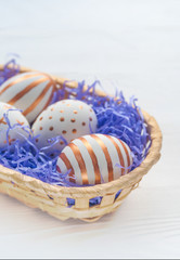 Golden Easter eggs in basket with straw on wooden rustic vintage background.