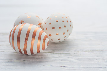 Golden Easter eggs on white wooden rustic vintage background.