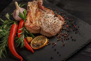 Grilled meat and vegetables on a black rustic background.