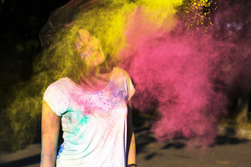 Pretty  young woman with short hair playing with yellow and pink Holi paint