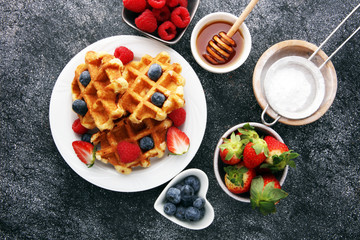 Traditional belgian waffles with fresh fruit and powder sugar on wooden board