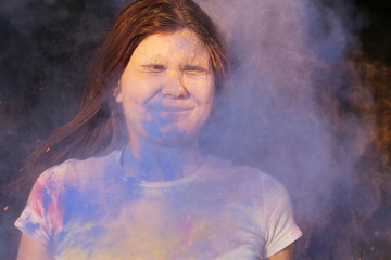 Stunning young woman with exploding blue powder celebrating Holi festival