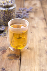 Herbal tea with lavender. In a glass with double walls. A bank of dried herbs for tea. Free space for text or a postcard.