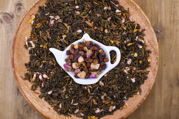 Dried herbs for tea, on a wooden round plate. Free space for text.