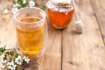 Aromatic herbal tea. In a glass with double walls. Branch with flowers. Bank with honey. Free space for text or a postcard.