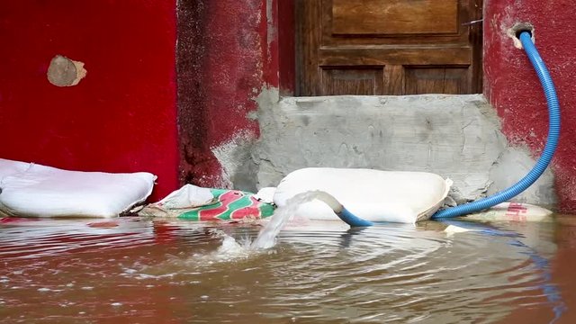 A pump hose pumps flood water from a building into the flooded street