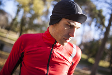 cyclist posing in park in autumn with a cap