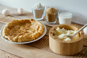 fresh milk, flour, sugar, eggs and cake on a wooden table prepared for applying the cream