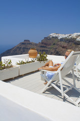 Tourist woman enjoying view of beautiful white village of Oia with Caldera and mediterranean sea....