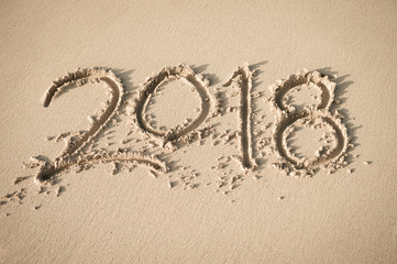 New Year 2018 message handwritten on a smooth sand beach in soft morning sunlight