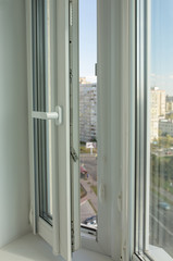 Open pvc window on the background of multi-storey apartment buildings