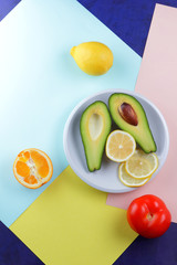 Avocado, lemon and half orange on a colorful background, tropical fruit pop art, vegetarian breakfast, Asian cuisine, avocado pop art, citrus, orange with avocado