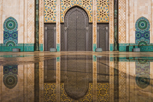 view of Hassan II mosque's big gate reflected on rain water - Casablanca - Morocco