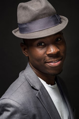 Portrait of attractive young black male studio with hat cheesy smile on dark background