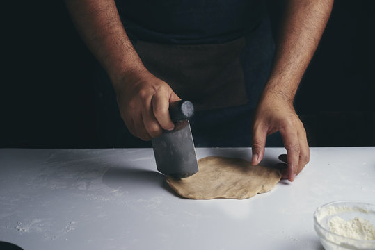 Midsection of man cutting dough while making food