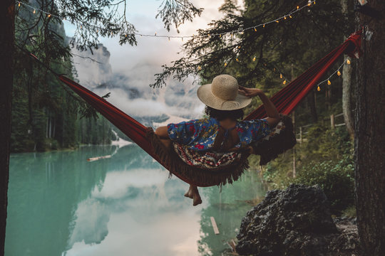 Rear View Of Woman Sitting In Hammock Over Lake