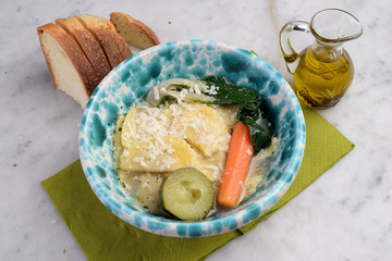 Terracotta lemmo with pasta agnolotti in broth
