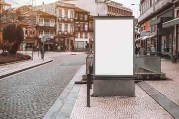 Vertical empty billboard placeholder template on pavement stone street with metro entrance behind...