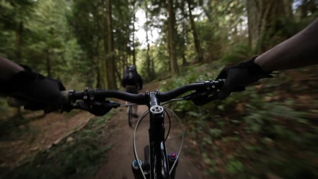 POV lockdown shot of mountain bikers riding bicycle on footpath at forest