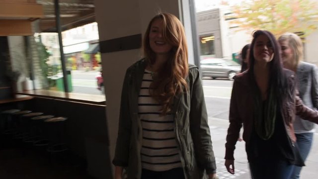 Handheld shot of female friends entering restaurant