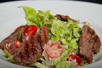 Veal salad, salad with large slices of veal and fresh vegetables on a plate