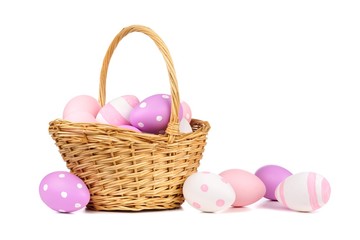 Easter basket filled with colorful hand painted pink, purple and white Easter Eggs over a white...